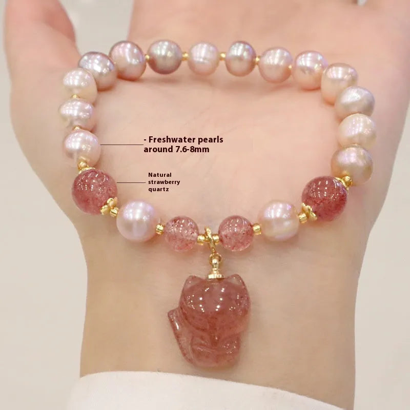 Women's light pink freshwater pearl bracelet with strawberry quartz and fox charm on wrist