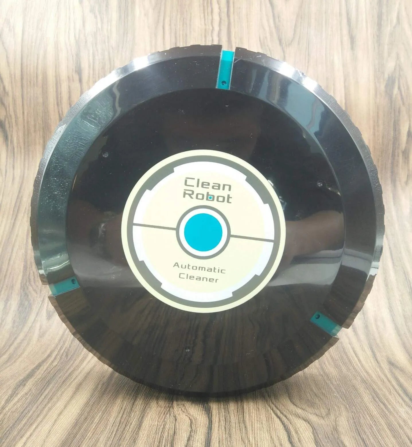 Black or white automatic floor sweeper robot on a hardwood floor.