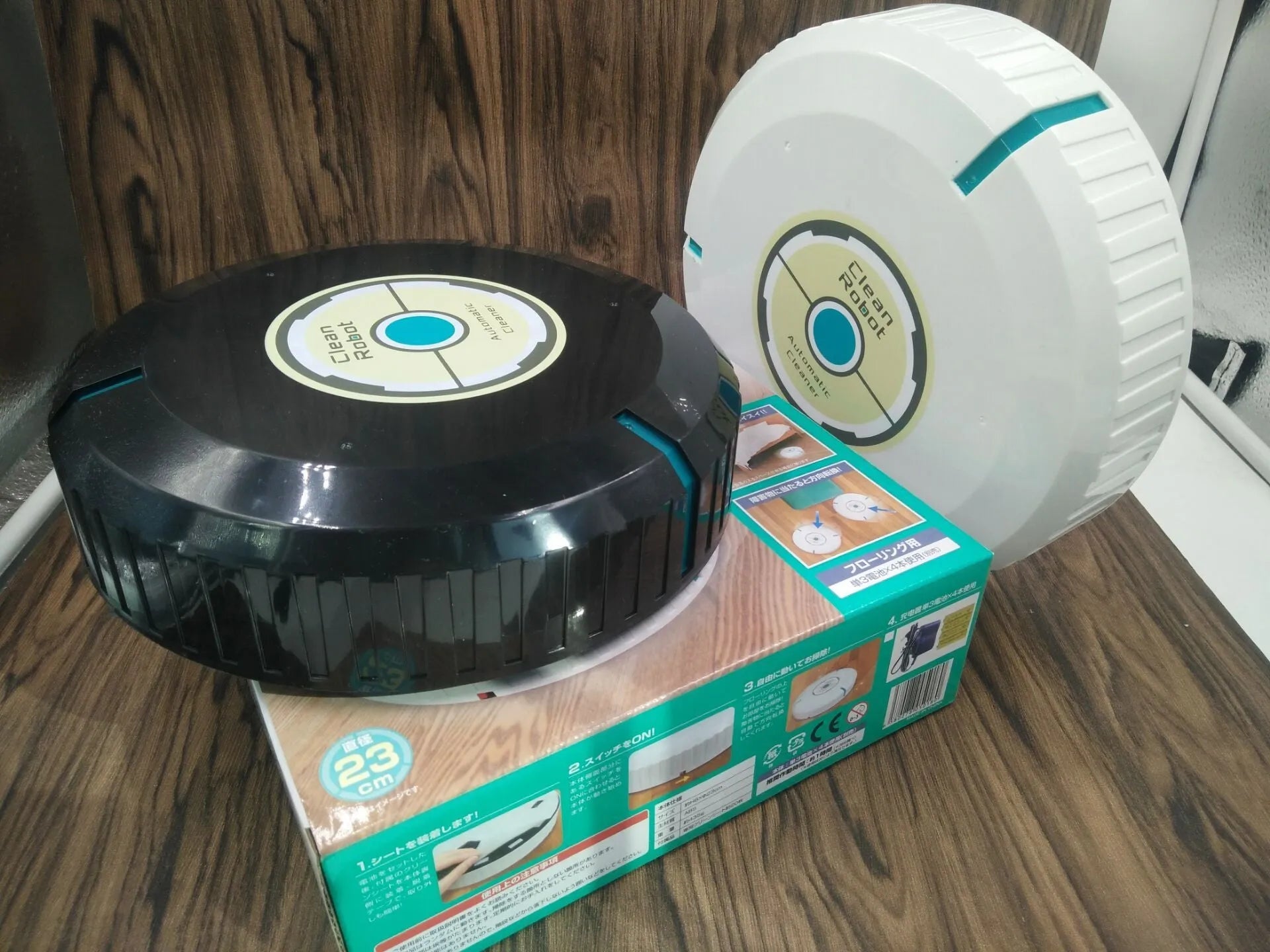 Black or white automatic floor sweeper robot on a hardwood floor.