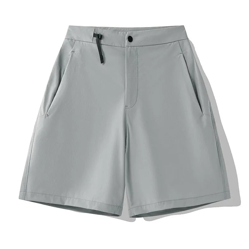 Man wearing khaki athletic shorts with four-way stretch, demonstrating movement for running or climbing.