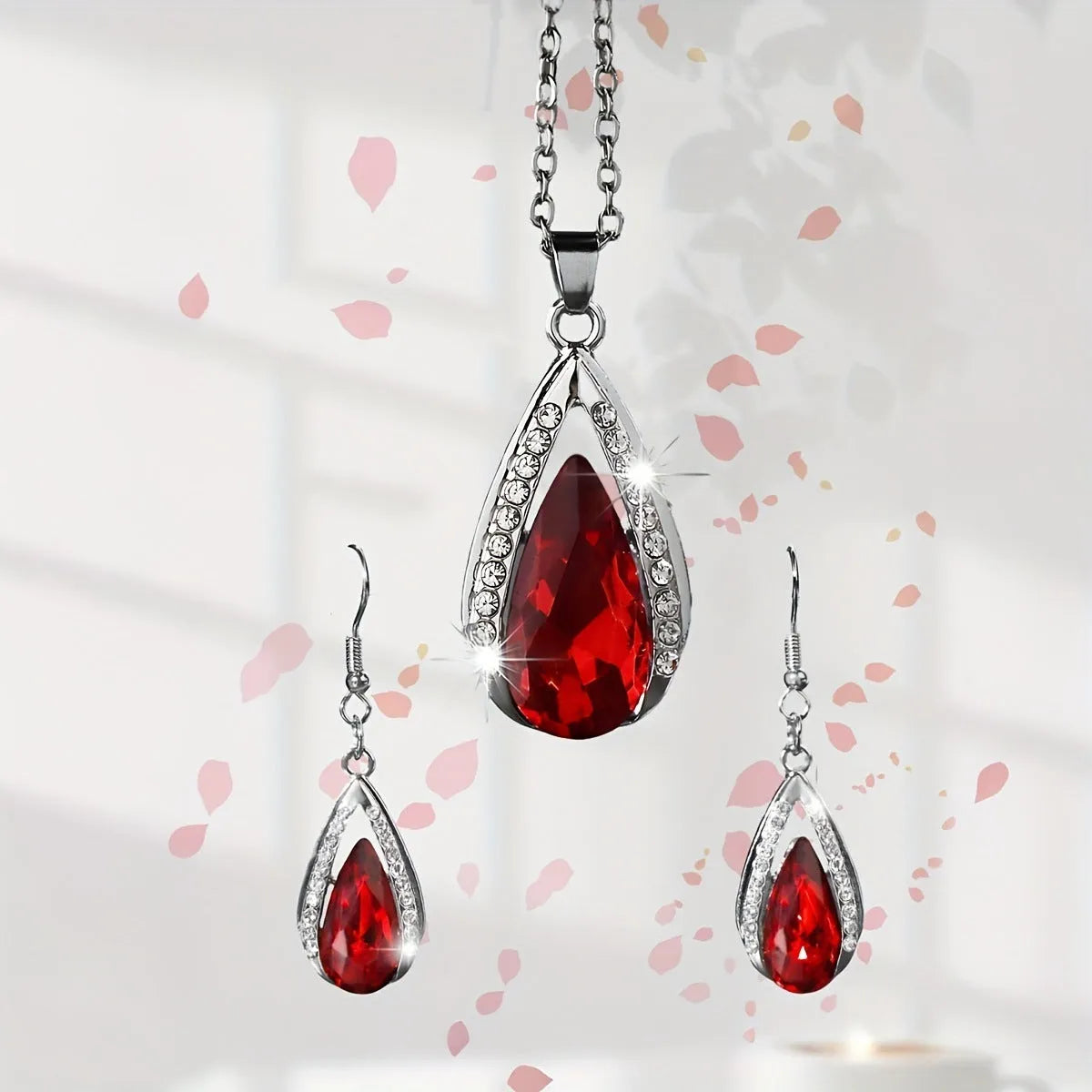 Black and red teardrop glass pendant necklace and matching earrings set on a grey background