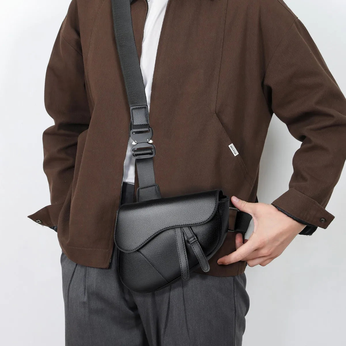 Unisex saddle shoulder crossbody chest bag in black synthetic leather with stitching and splicing details