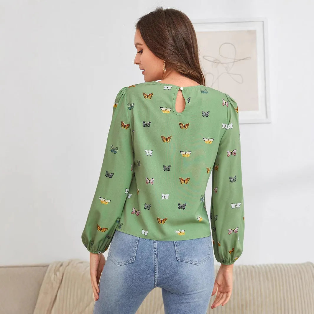 Green women's long-sleeved shirt with butterfly print, showing loose fit and long sleeves.