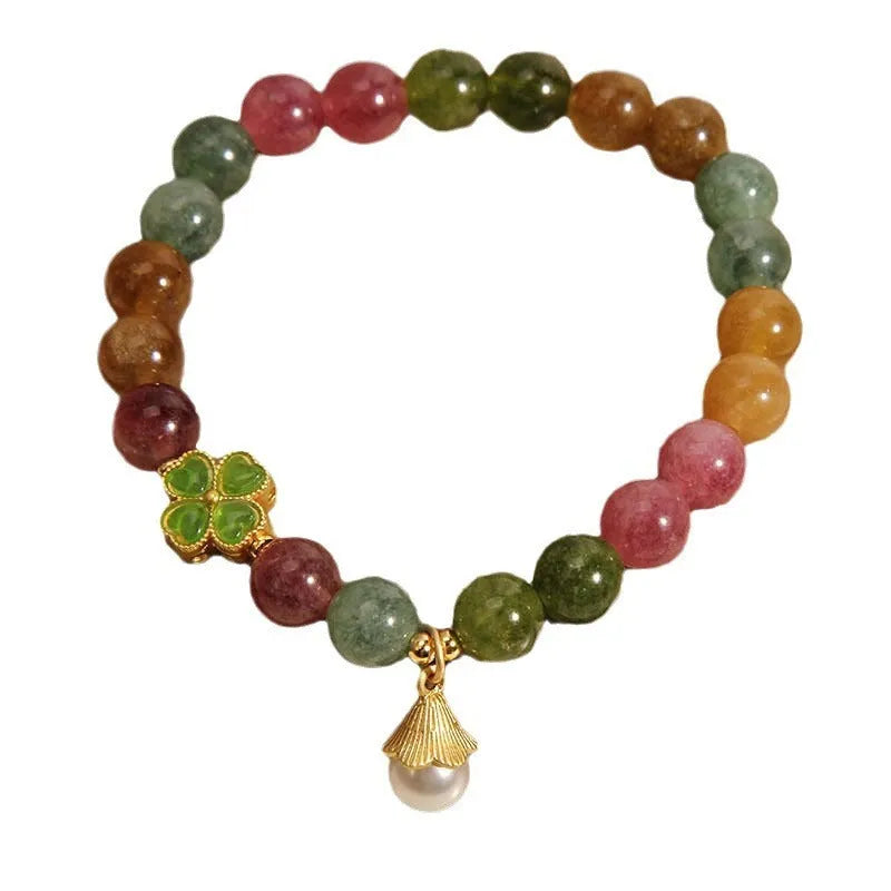 Natural colour tourmaline bracelet with four-leaf clover pearl pendant, geometric drop shape on woman's wrist.