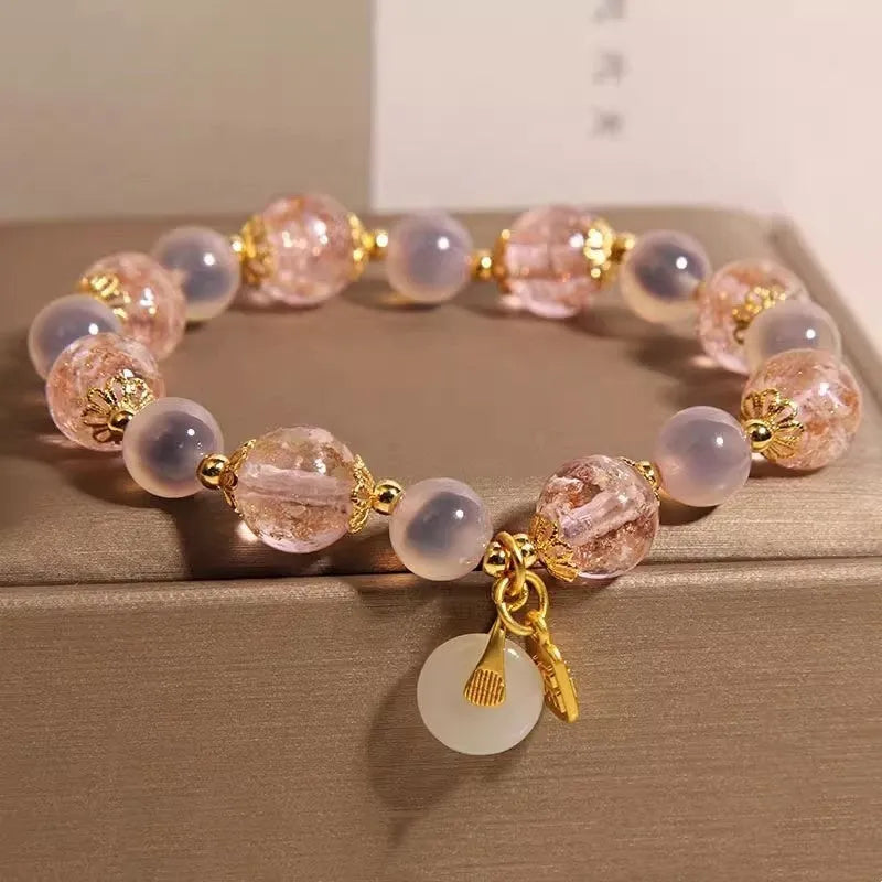 Close-up of a women's pink agate heart bracelet with a luminous glaze and a silver peace buckle clasp.