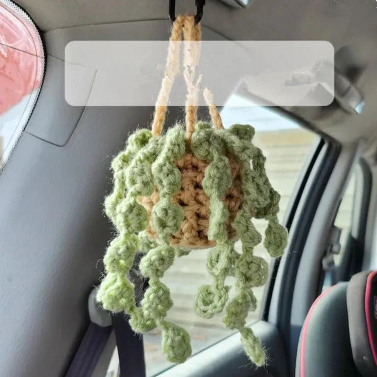 Green and white knitted wool car plant ornament hanging from a rope
