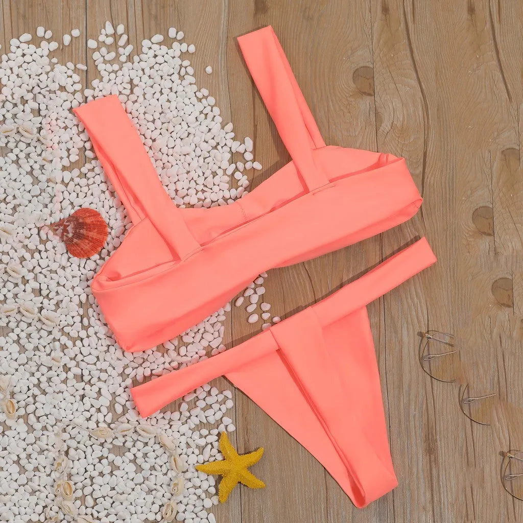Solid colour orange split bikini swimsuit with high-cut legs on a model by the pool