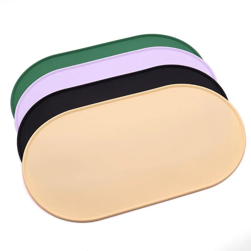 Beige silicone cat feeding mat with raised edges holding a food and water bowl on a wooden floor.