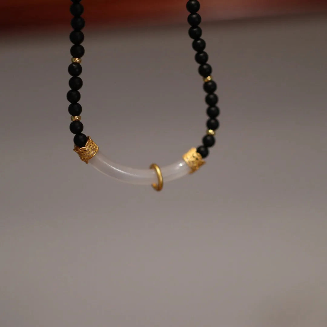 Close-up of a Chinese style U-shaped necklace with a frosted black agate and white chalcedony pendant on a silver ball bead chain.