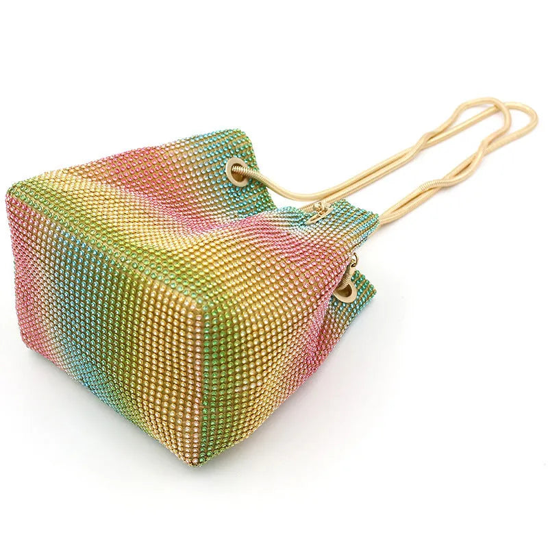 Rainbow coloured soft bucket handbag covered entirely in sparkling rhinestones with a top handle.