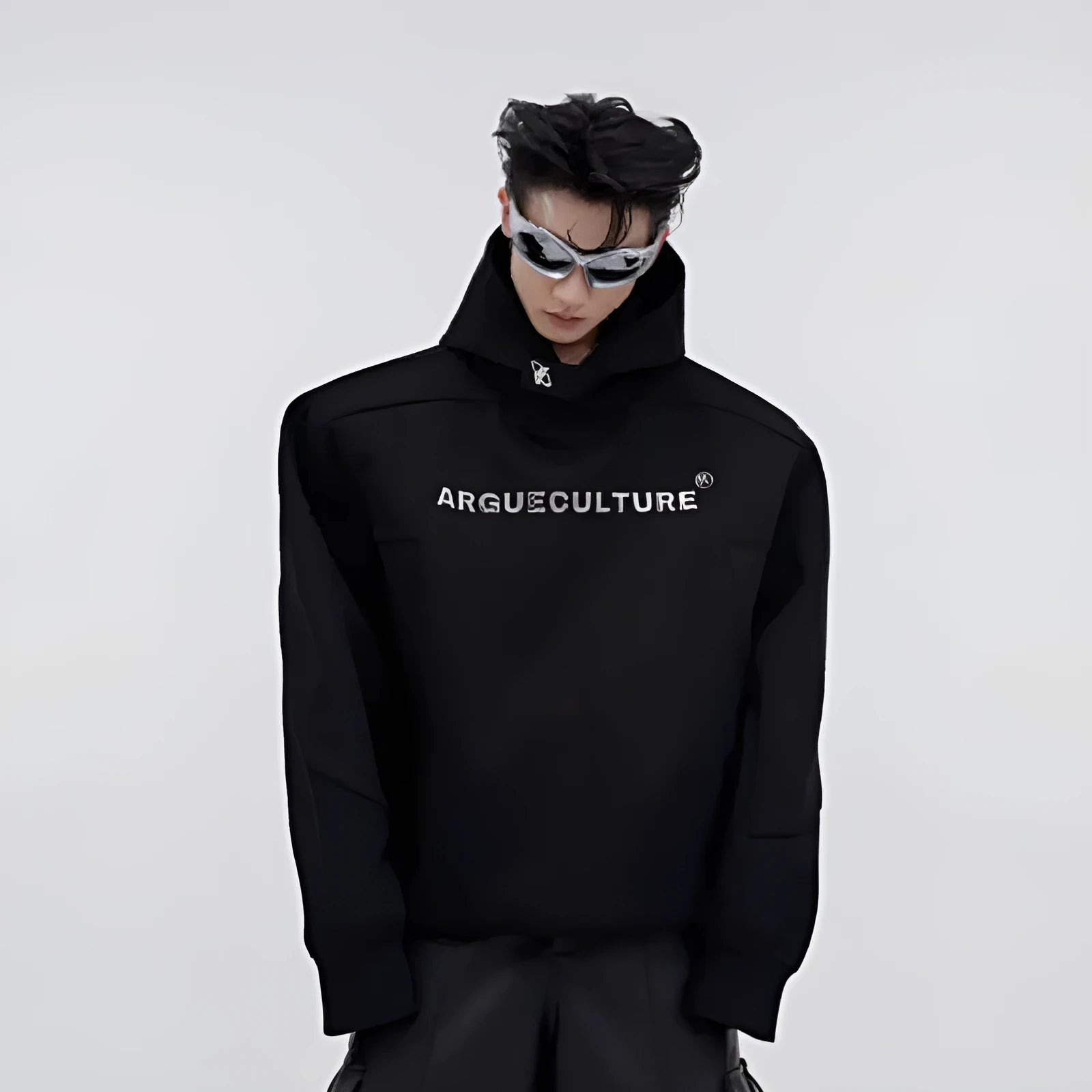 Man wearing a loose red hooded sweater with metallic 3D printing and structured shoulder pads.