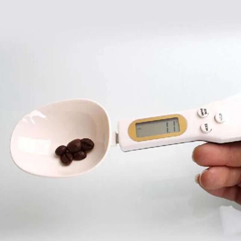 White digital spoon kitchen scale with LCD display showing weight measurement.