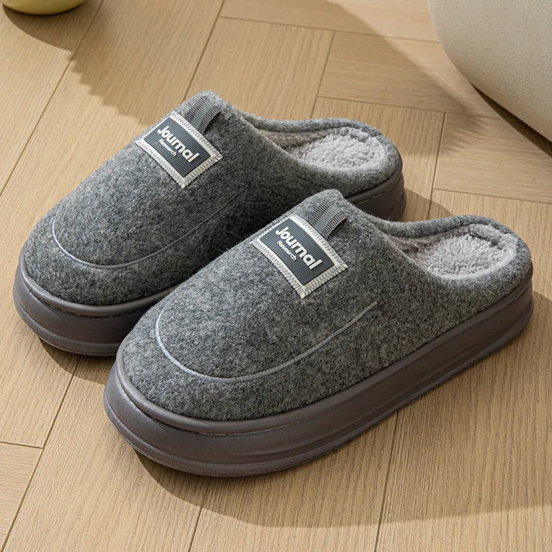 Men's grey suede slippers with a thickened sole shown on a wooden floor.