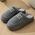 Men's grey suede slippers with a thickened sole shown on a wooden floor.