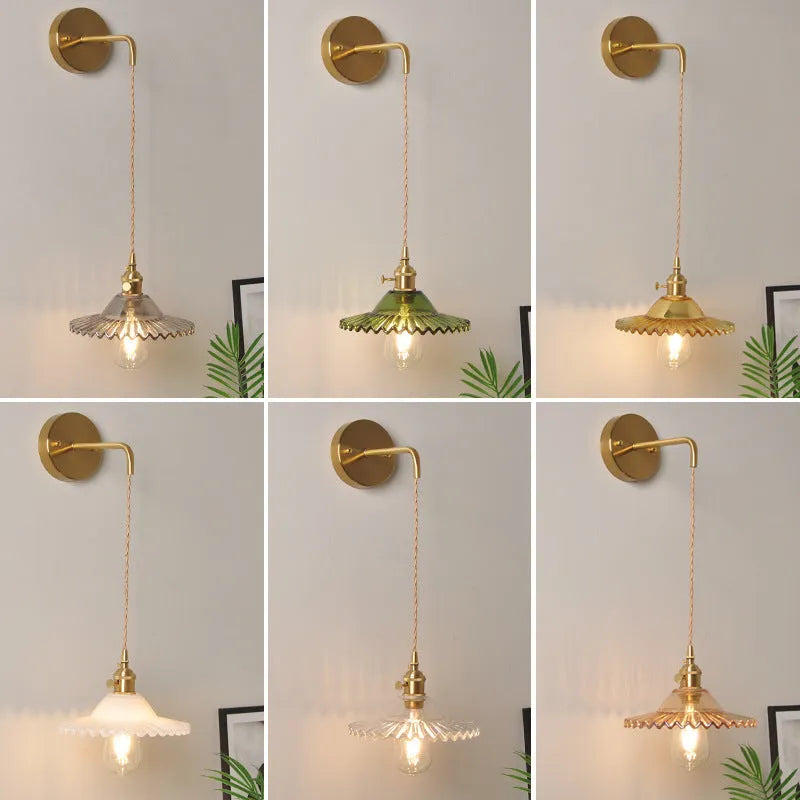 Retro brass lotus wall lamp with a 22cm green glass shade mounted on a copper base beside a bed.