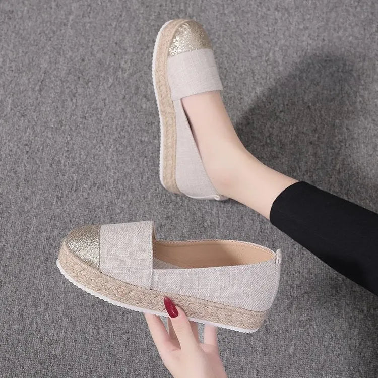 Plus size beige canvas slip-on flat shoes with a round toe on a white background.
