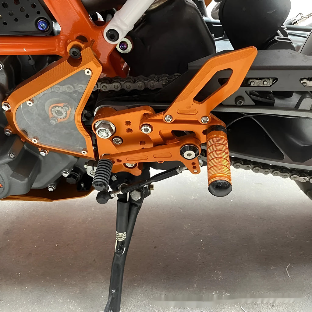 Black and orange KTM Duke motorcycle rear shift pedal support bracket assembly.