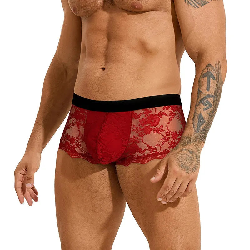 Men's black lace briefs with hollow-out see-through panels on a grey background.
