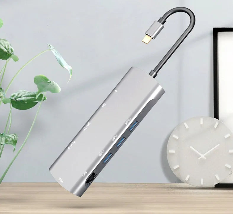 Grey aluminium USB-C docking station with multiple ports including HDMI, VGA, and USB, showing its 140mm attached cable.