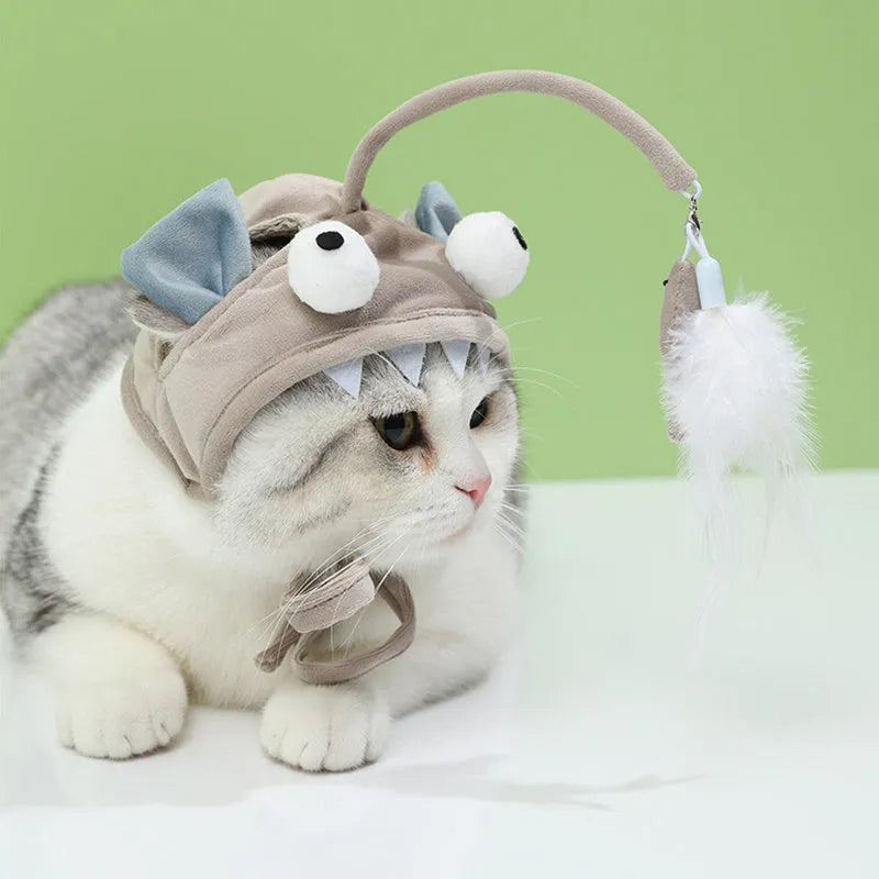 Grey dinosaur-themed head-mounted cat toy with feathers and big eye fish design on adjustable band