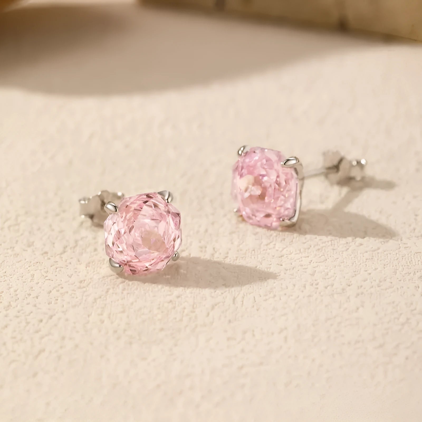 A pair of sterling silver stud earrings featuring a detailed rose flower design.