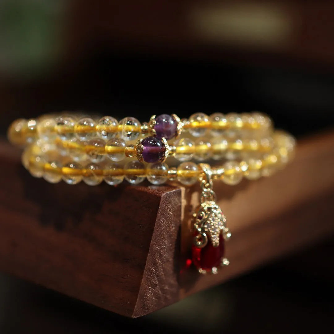 Natural Brazilian rutilated quartz bracelet with gold accents and Chinese-style charms on adjustable cord