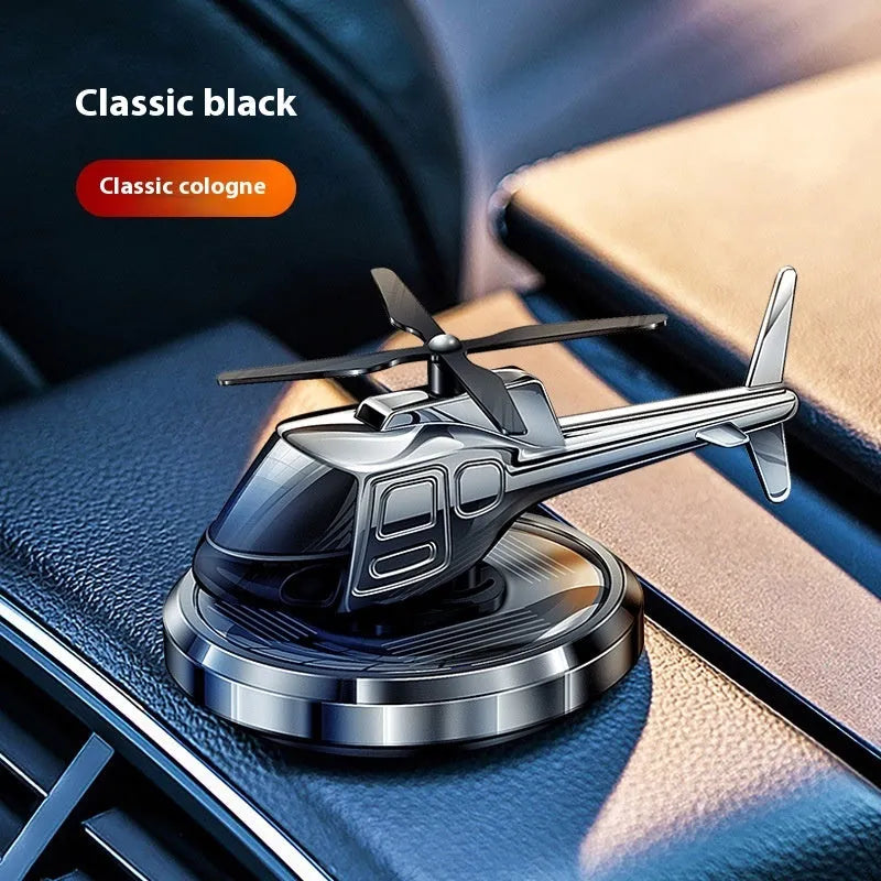 Silver metal solar-powered helicopter car air freshener spinning on a car dashboard