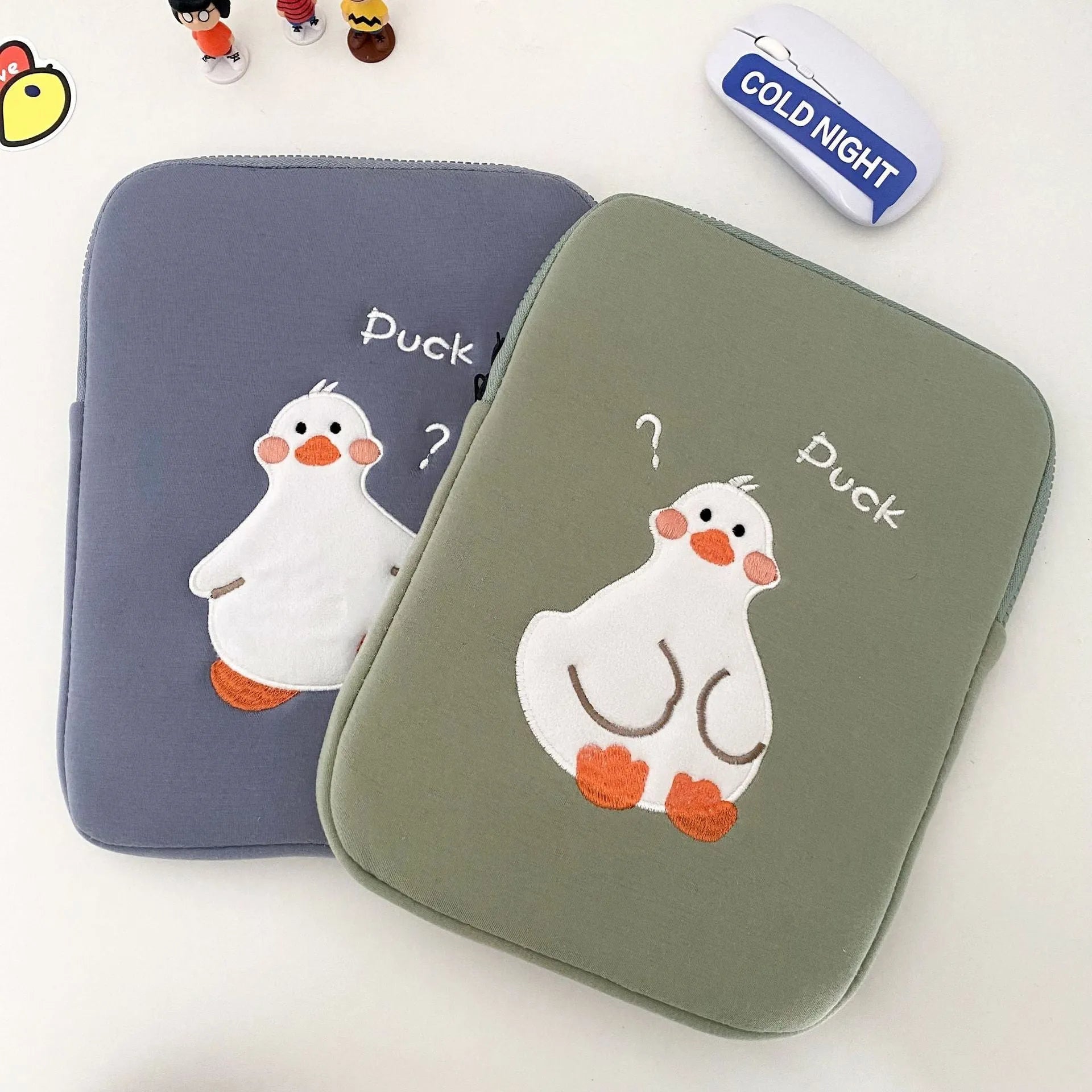 Blue cotton tablet case with embroidered cartoon duck design, showing zipper closure and protective frame.
