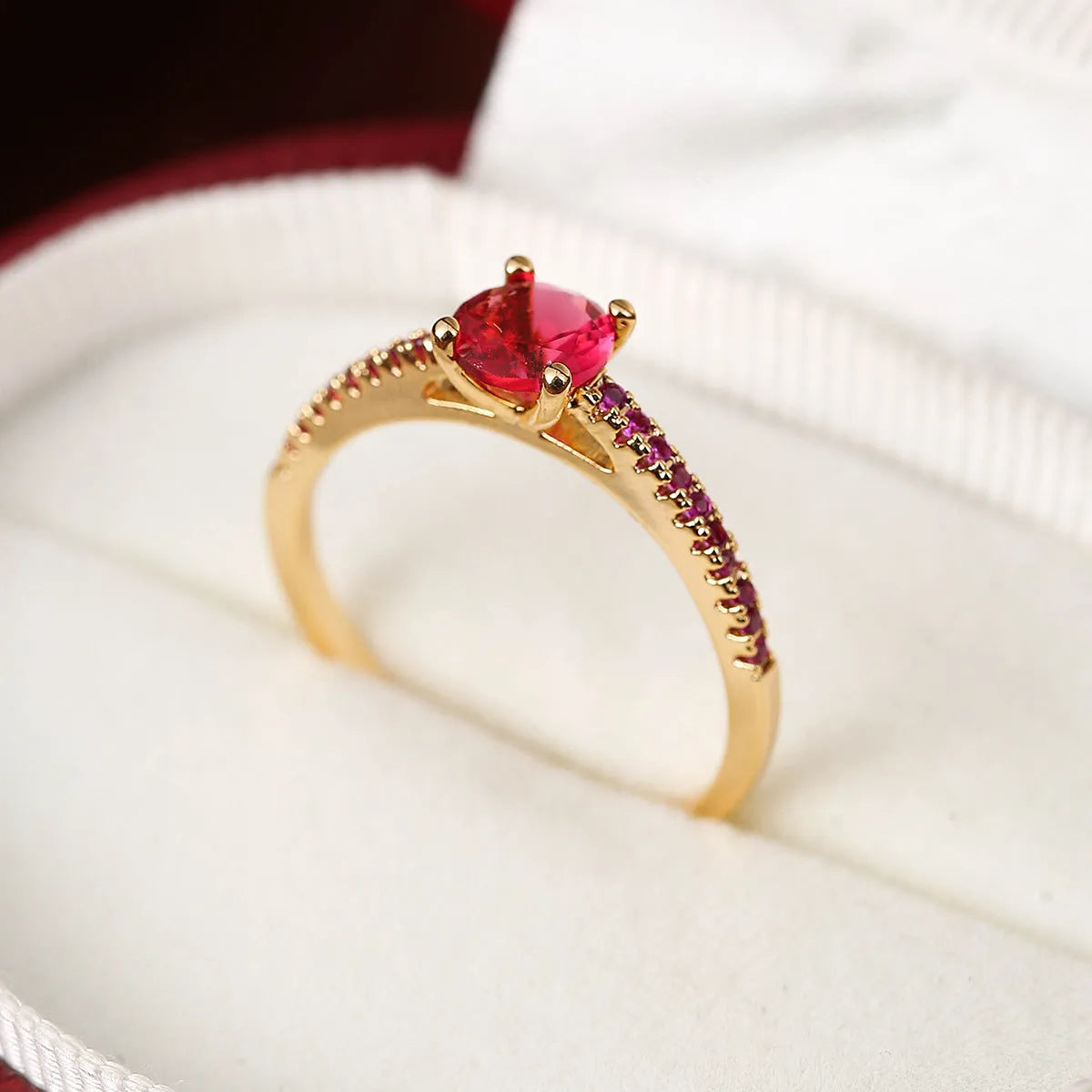 A hexagonal geometric ring with a zircon stone, shown in a gun black and rose red electroplated finish on a finger.