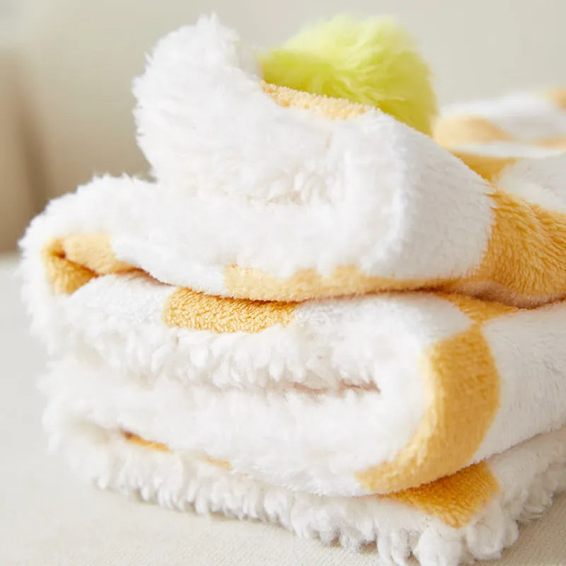 Plush pet blanket with plaid pattern and fur ball decoration for cats and dogs on sofa