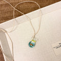 Women's joker motif pendant necklace on a braided cotton and linen clavicle chain.