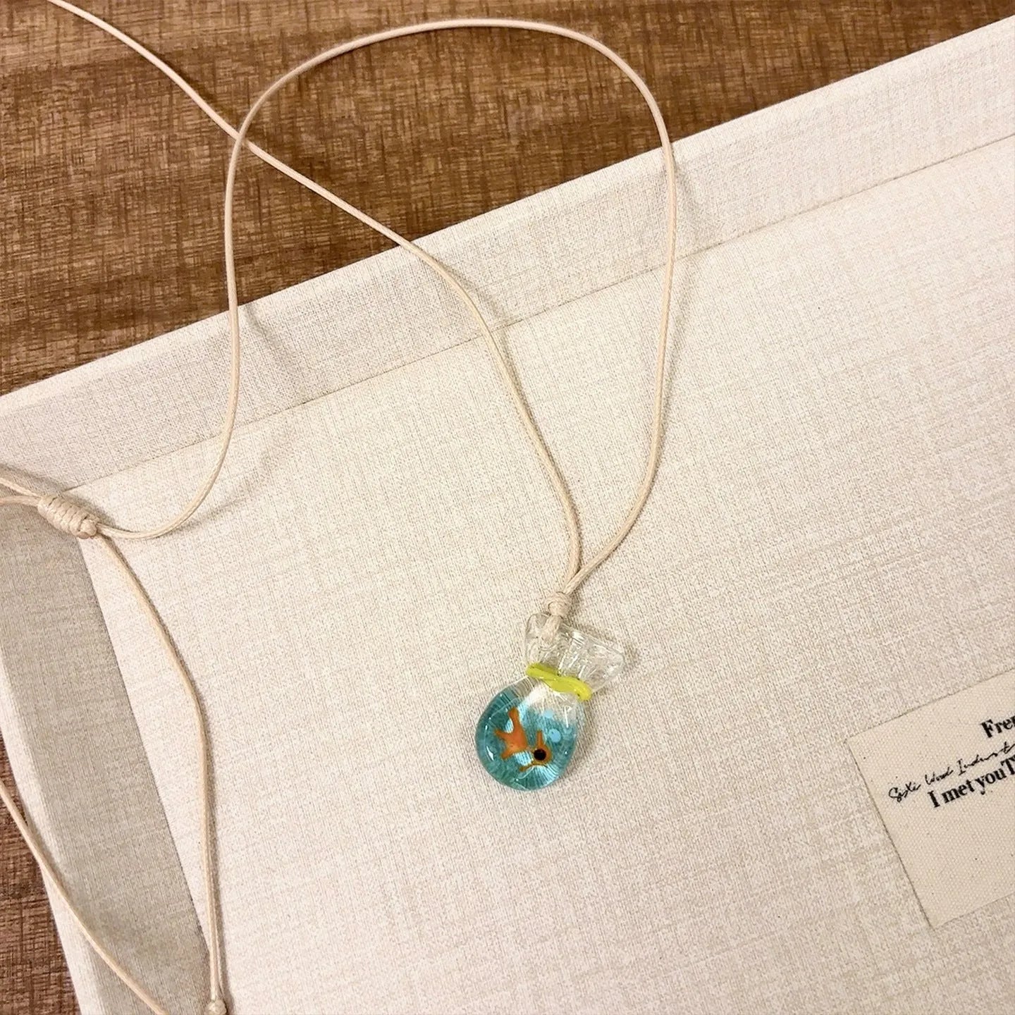 Women's joker motif pendant necklace on a braided cotton and linen clavicle chain.