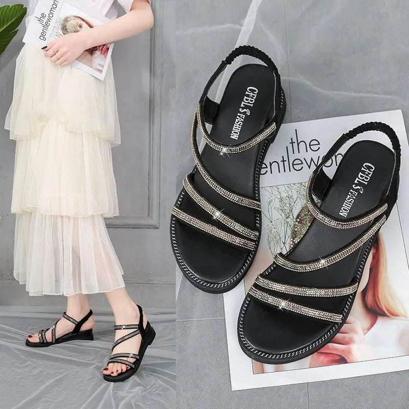 Women's gold flat sandals with round toe, elastic band, and rhinestone fairy decoration on a white background.