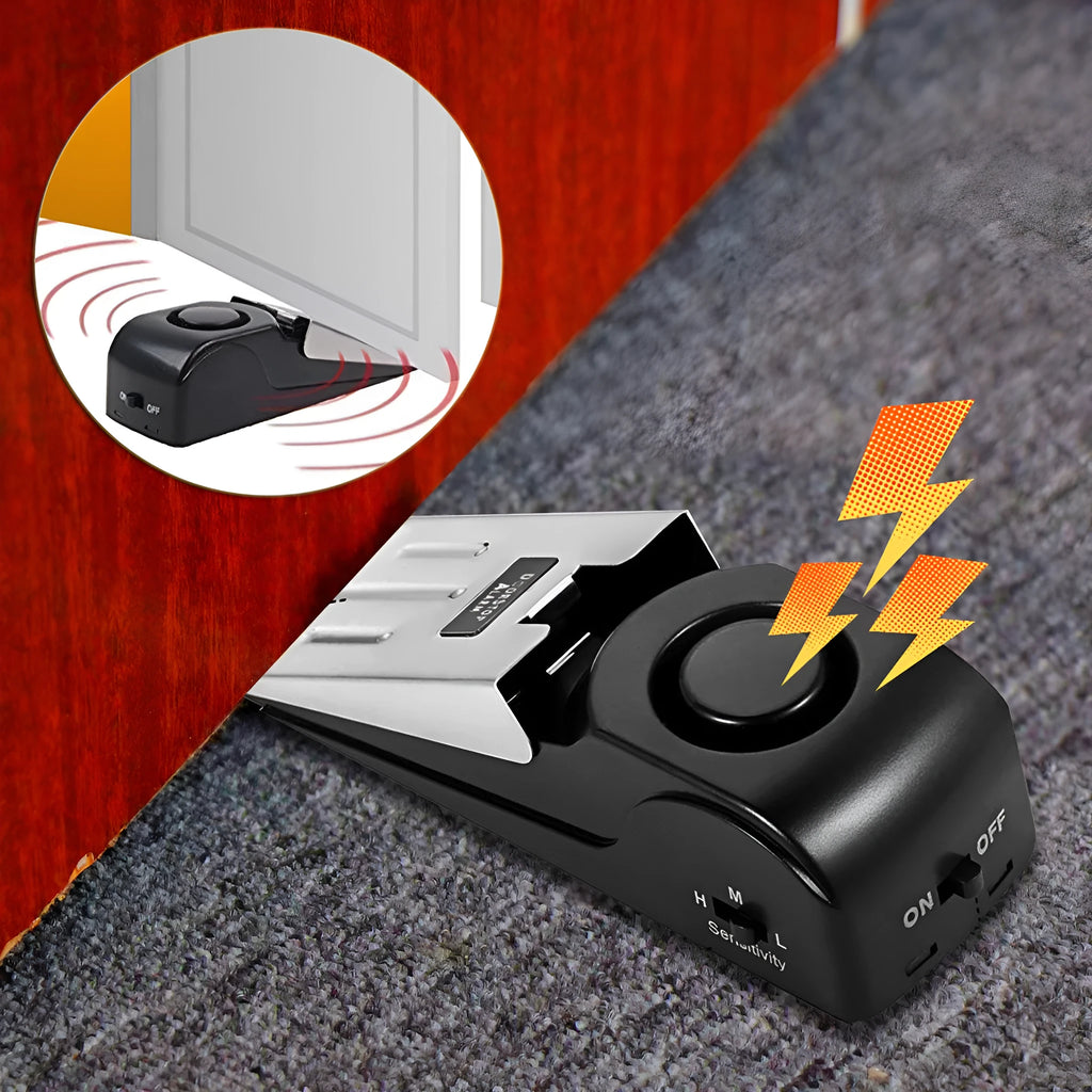 Black portable wedge door alarm with stainless steel cover placed against a hinged door.