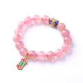 Close-up of a pink strawberry quartz crystal bracelet with hand-woven Ruyi design and letter detailing.