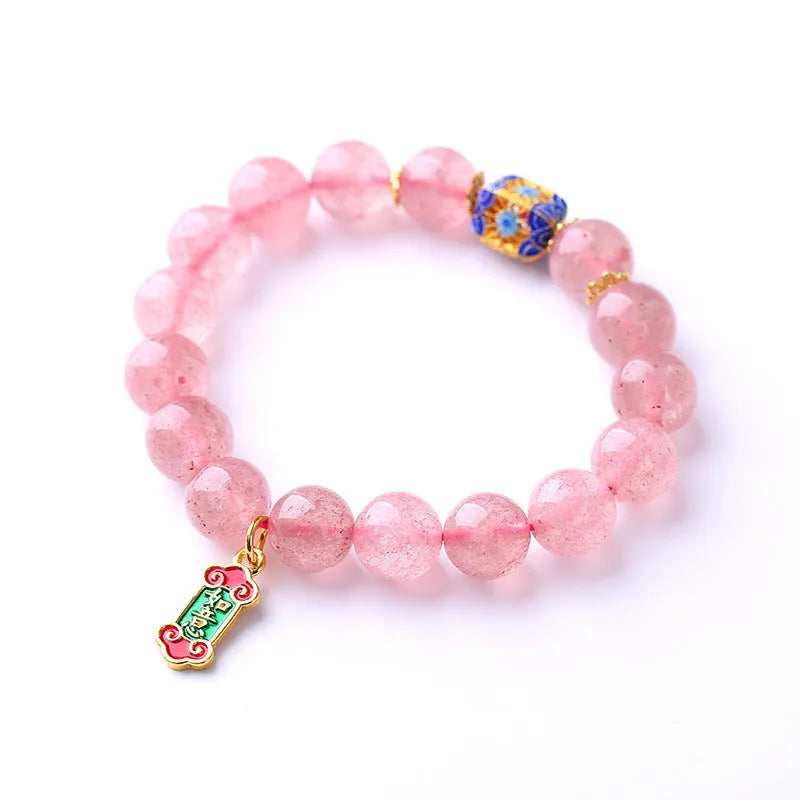 Close-up of a pink strawberry quartz crystal bracelet with hand-woven Ruyi design and letter detailing.
