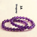 Natural violet amethyst crystal bead bracelet with polished, scattered beads on a neutral background.