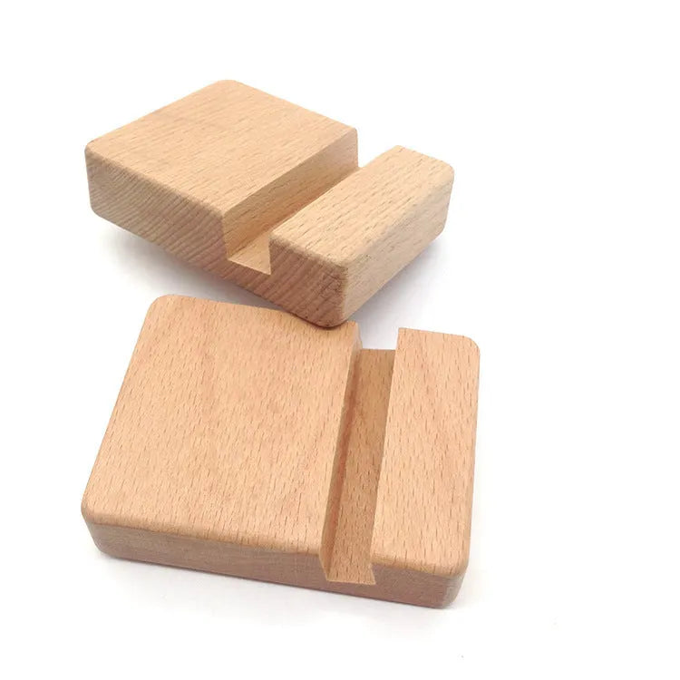 Solid beech wood mobile phone stand with a resin cow figurine and a slot for holding coins on a wooden desk.