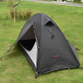 Single person green tunnel tent with aluminium poles pitched in a forest, showing mesh door and waterproof flysheet.