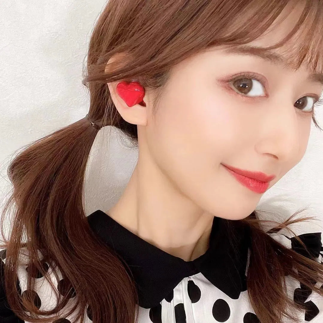 Heart-shaped wireless Bluetooth earbuds in red or pink colours with charging cable
