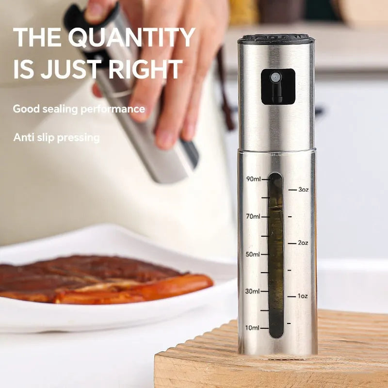 Stainless steel press spray oil injection bottle with glass body and 100ml capacity on kitchen countertop