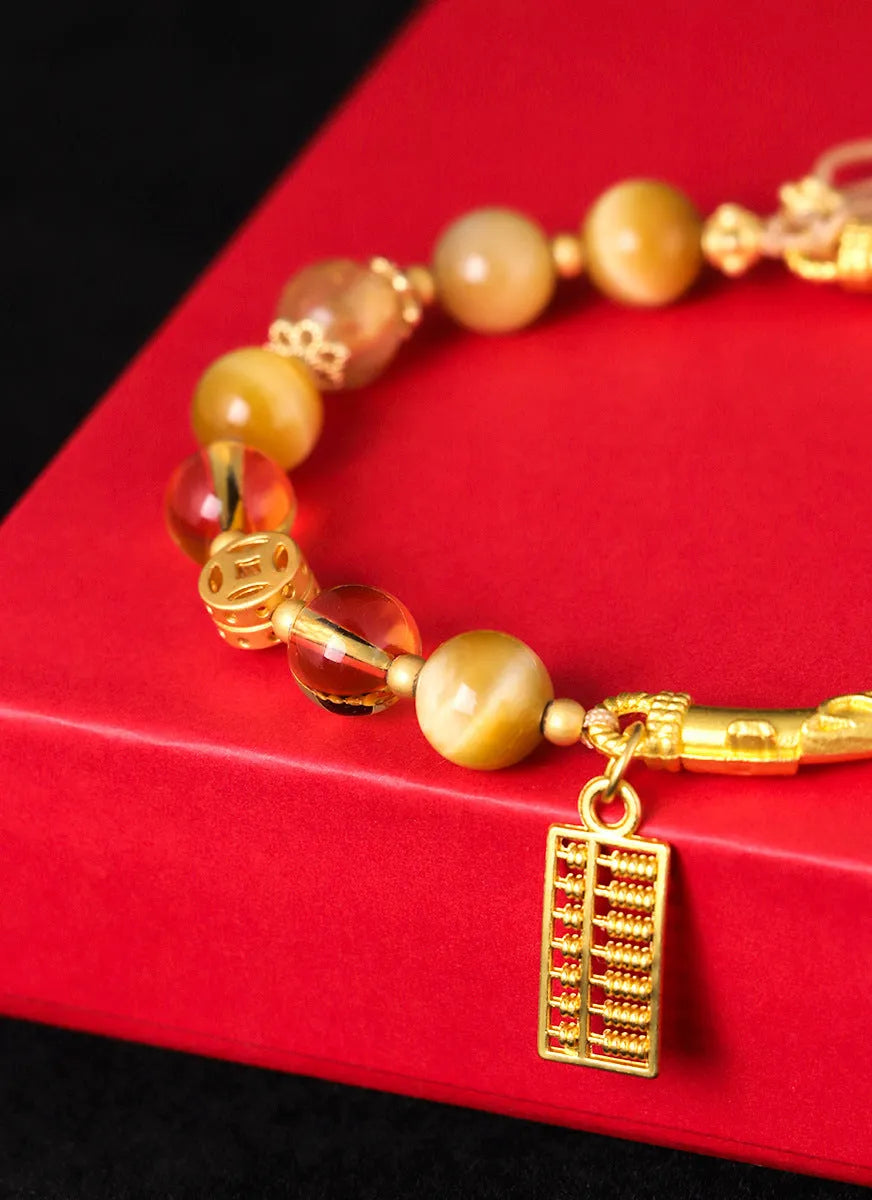 Close-up of a women's beaded bracelet with diamond-shaped tigereye and citrine stones and copper details.