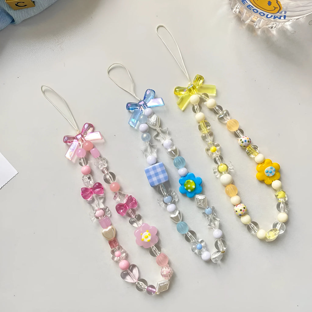 Adjustable rope wrist lanyard with blue plastic flower beads attached to a mobile phone.