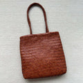 Brown handmade cowhide leather woven tote bag with a three-dimensional front pocket.