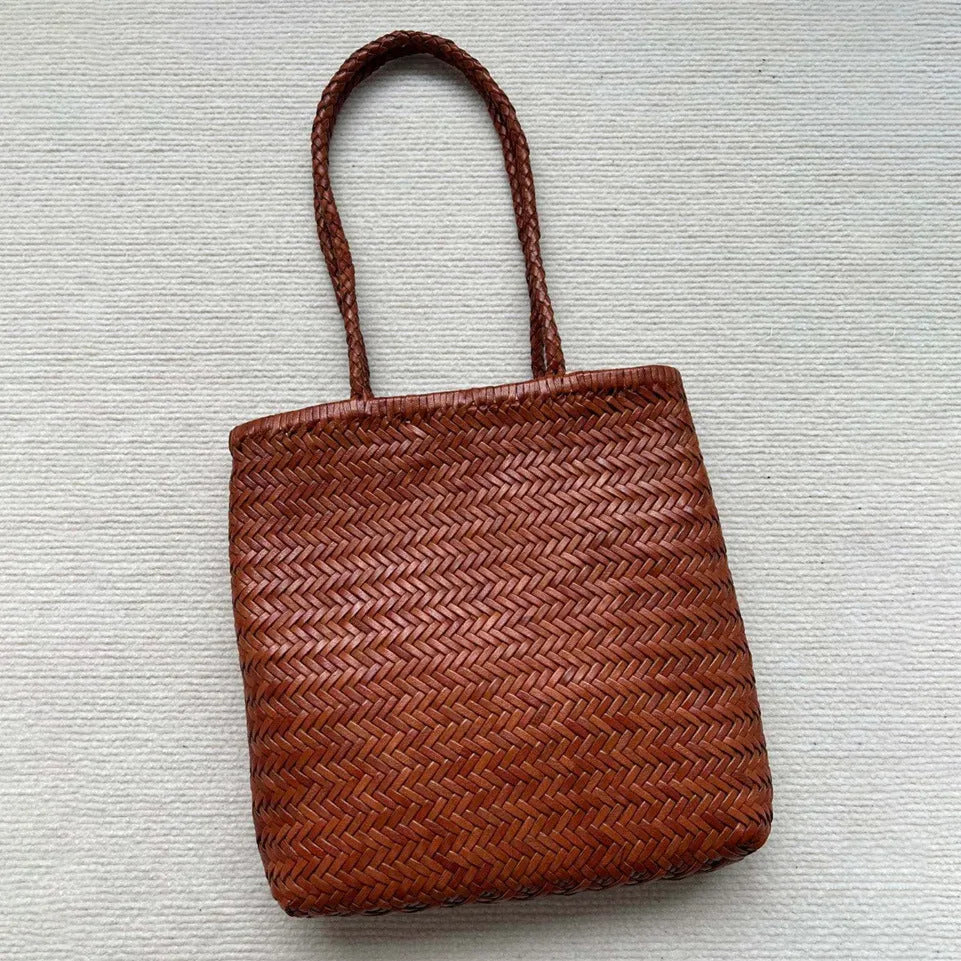 Brown handmade cowhide leather woven tote bag with a three-dimensional front pocket.