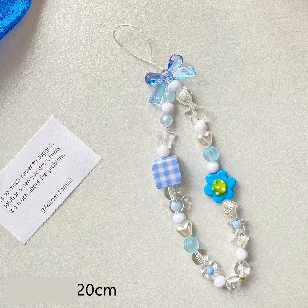 Adjustable rope wrist lanyard with blue plastic flower beads attached to a mobile phone.