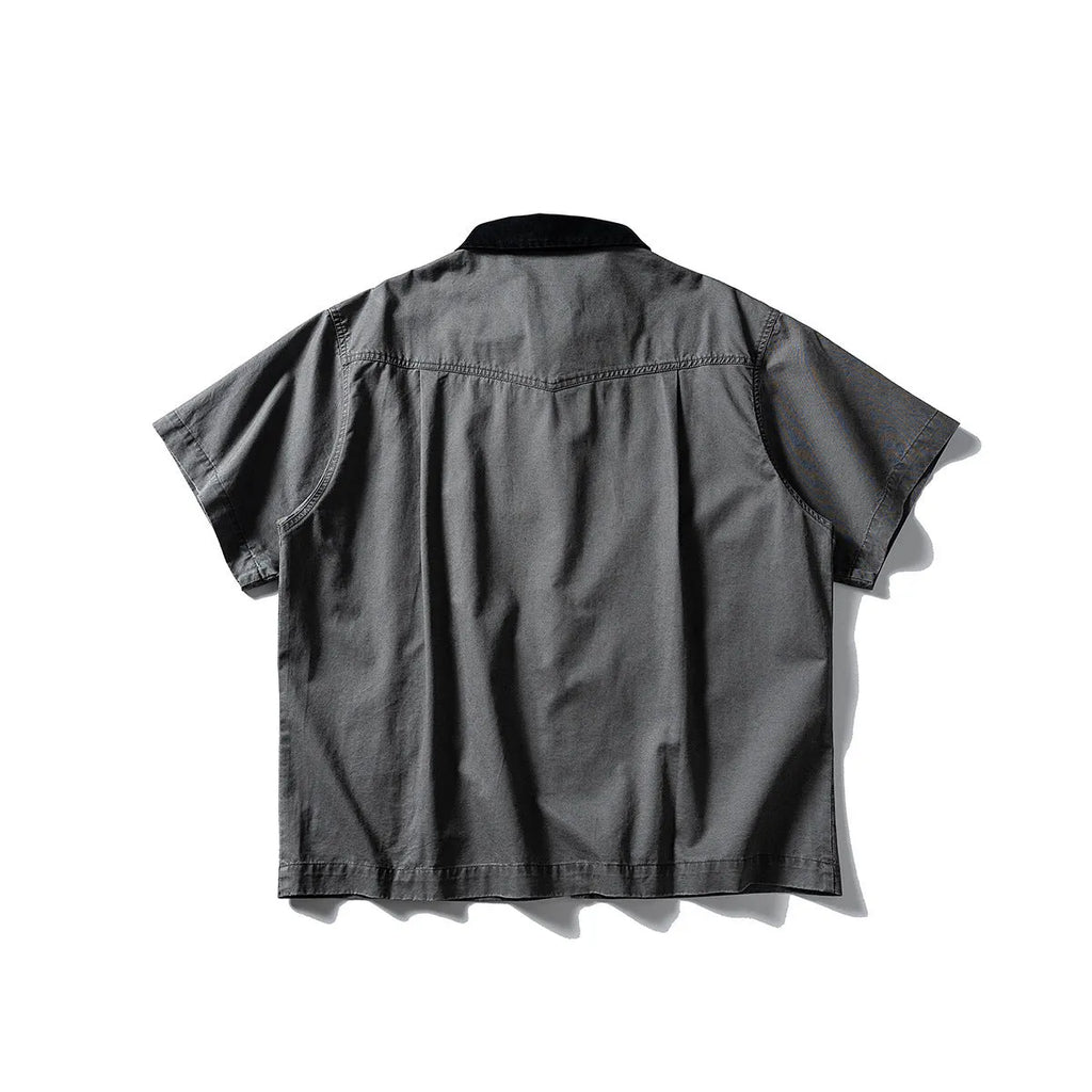 Washed grey cotton overalls shirt with short sleeves and a loose cardigan style on a hanger.