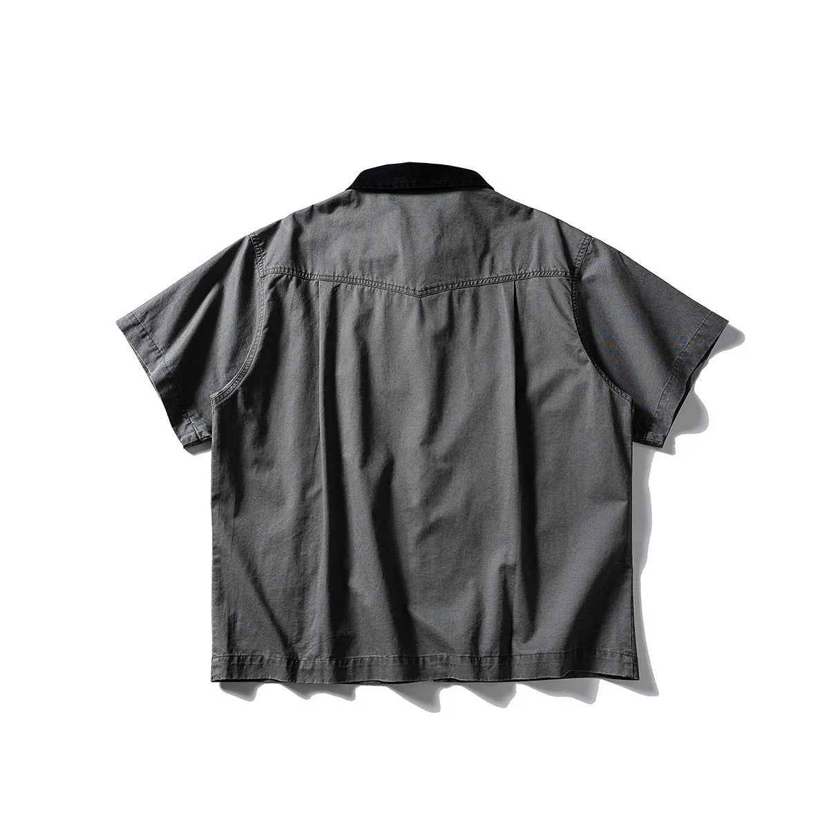 Washed grey cotton overalls shirt with short sleeves and a loose cardigan style on a hanger.