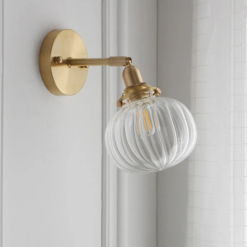Hand-blown transparent water ripple glass wall lamp mounted on a beige wall, emitting a soft amber glow