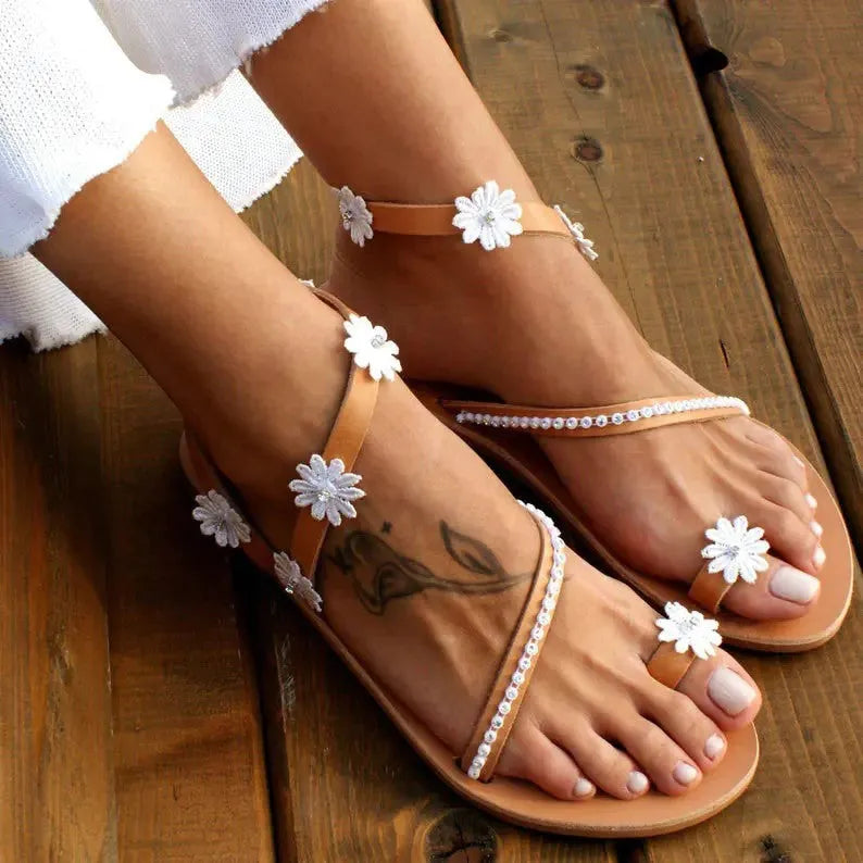 Brown ladies flat sandals with floral pattern, herringbone toe, and rubber sole.